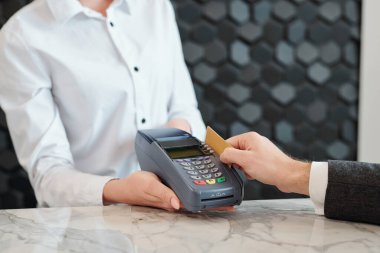Mağazadaki ya da oteldeki ödeme terminalinden kredi kartı geçiren tanınmayan bir adamın yakın çekimi.