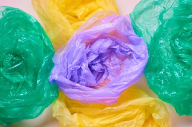 Horizontal from above flat lay shot of empty multi-coloured plastic garbage bags on neutral background