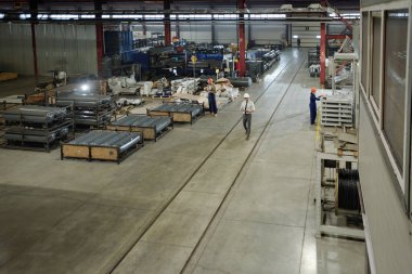 Dev otomasyon makinelerinin parçalarıyla çalışan bir grup mühendis ile modern endüstriyel fabrikanın büyük atölyesinin görüntüsü