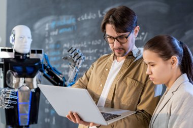 Özel yazılımın yardımıyla çalışan otomasyon robotunun sunumunu yapan bilgisayar teknolojileri öğretmeni veya programcı