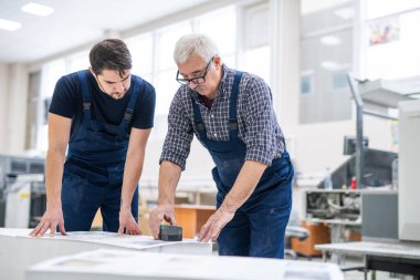 Genç işçilere matbaada basılı kağıtların nasıl damgalandığını gösteren ciddi bir uzman.
