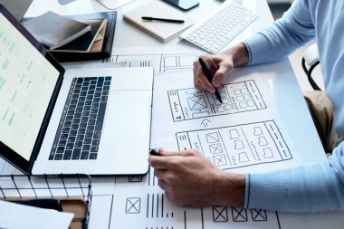 Kağıt üzerinde yeni yazılım sürükleme şeması üzerinde çalışan tanınmayan uygulama geliştiricisinin yatay yüksek açılı görüntüsü