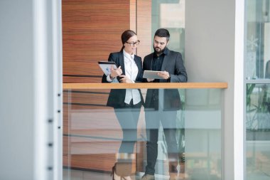Ofis koridorunda çevrimiçi bilgileri incelerken dijital tablet kullanan genç analistler