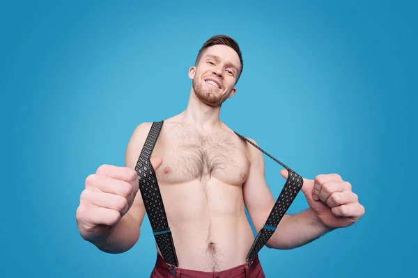 Portrait Cheerful Sexy Guy Hair Chest Pulling Suspenders Blue Background — Stock Photo, Image