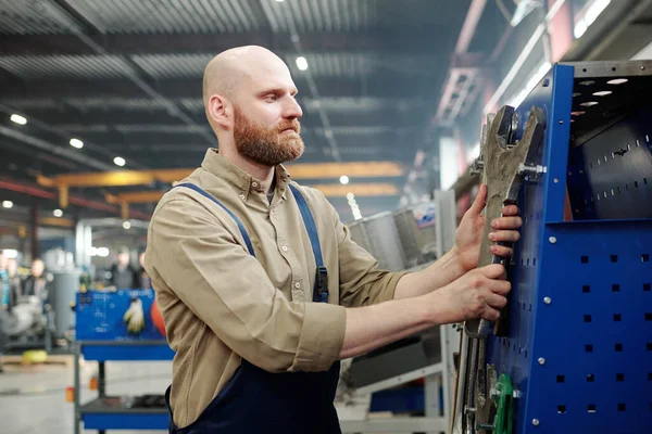 光秃秃的工作服工程师选择巨大的工业扳手在工厂进行技术工作 — 图库照片