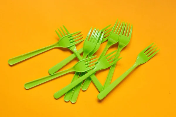 Disposable Light Green Plastic Forks Lying Bright Orange Background Horizontal — Stockfoto