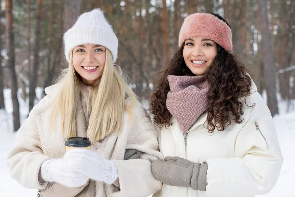 冬の日に一緒に屋外に立つスタイリッシュな暖かい服を着ている2人の若い女性の横中出しカメラの笑顔を見て — ストック写真
