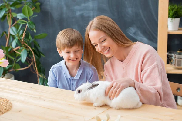 Alegre Madre Hijo Sentado Mesa Madera Jugando Con Conejo Blanco — Foto de Stock