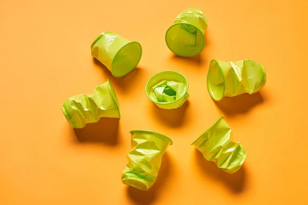 Used Disposable Light Green Plastuc Cups Lying Bright Orange Surface — Stok fotoğraf