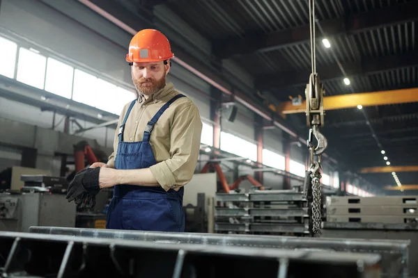钢制工作服和硬帽的轴承工程师 在工厂控制工作过程时 站在巨大的铁制细部 — 图库照片