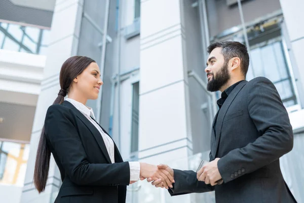 オフィスで挨拶しながら新しいビジネスパートナーと握手する女性の笑顔のビューの下で — ストック写真
