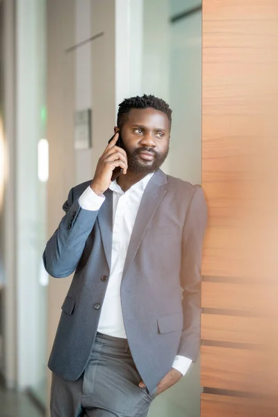 Tartalom Magabiztos Fiatal Fekete Üzletember Kabátban Áll Falnál Beszél Mobiltelefonnal — Stock Fotó