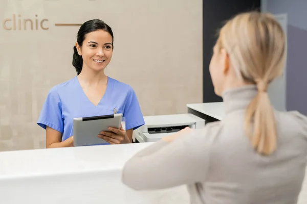 Jovem Assistente Feliz Com Tablet Balcão Recepção Frente Paciente Enquanto — Fotografia de Stock