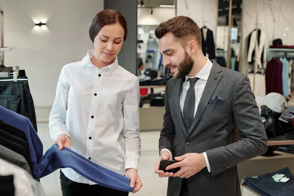 Sonriente Joven Consultor Clientes Mostrando Suéter Mientras Habla Con Hombre —  Fotos de Stock