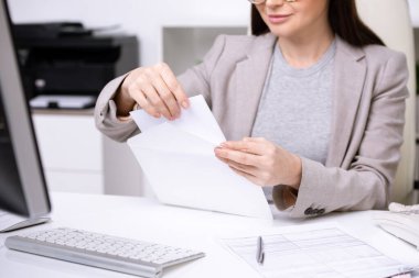 Genç iş kadını ya da bankacının elleri, bir müşteriye belge göndermeden önce katlanmış kağıdı beyaz zarfa koyuyor.