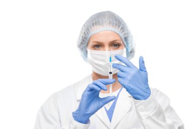 Cerrahi eldivenli kadın doktor iğneye hazırlanırken hava kabarcığını şırıngadan çıkarıyor.