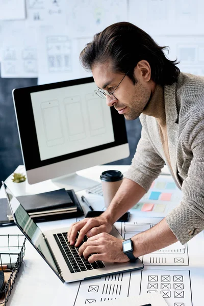 Uygulama Tasarım Şemaları Ofiste Dizüstü Bilgisayarla Masasında Duran Gözlüklü Yakışıklı — Stok fotoğraf