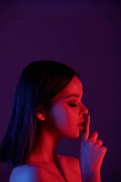 Güzel Genç Esmer Kadın Işaret Parmağını Ağzıyla Tutarak Izolasyonda Karanlık — Stok fotoğraf