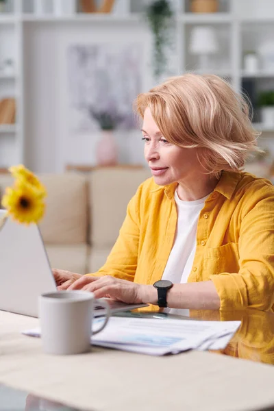 Pretty Blond Mature Female Yellow Jacket Sitting Desk Front Laptop — Stock Photo, Image