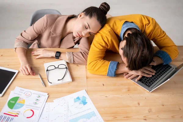 两个疲惫不堪的年轻人躺在手提电脑键盘上打瞌睡 一个是下班后睡在他肩上的姑娘 — 图库照片