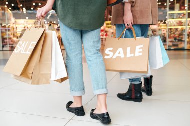 Kâğıt torbalı tanınmayan bir kadının alışveriş merkezine arkadaşlarıyla alışverişe gittiği yakın plan.