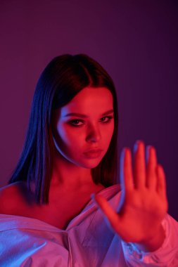 Genç, sert esmer, sana bakıyor ve elini önündeyken seni karanlık arka planda uzak tutuyor.