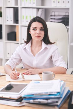 İçerik kadın ofis yöneticisinin portresi masada oturuyor ve düzenleyiciyle yazıyor.