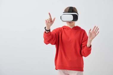 Kırmızı kapüşonlu ve VR kulaklıklı çağdaş genç kız hazırlanırken veya sunum yaparken sanal ekrana bakıyor.