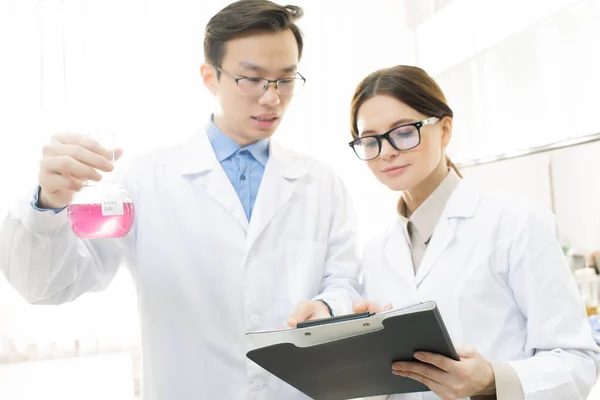 Mladý Asijský Vědec Nebo Chemik Drží Zobák Růžovou Tekutou Látkou — Stock fotografie