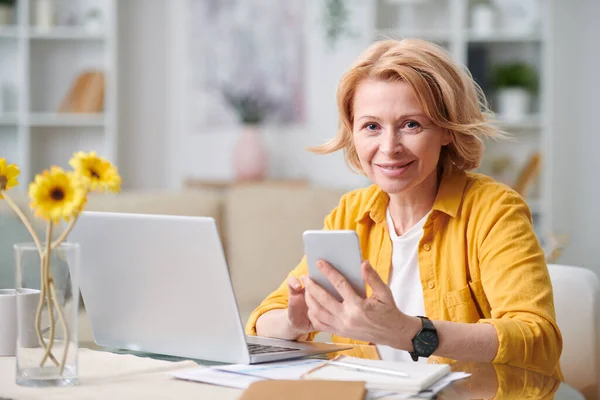 Smiling Mature Blond Businesswoman Smartphone Looking You While Working Remotely — Stock Photo, Image