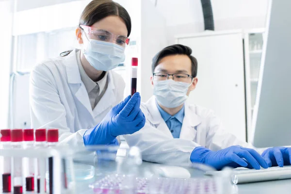 Joven Investigadora Sosteniendo Frasco Con Sustancia Líquida Oscura Mientras Estudia — Foto de Stock