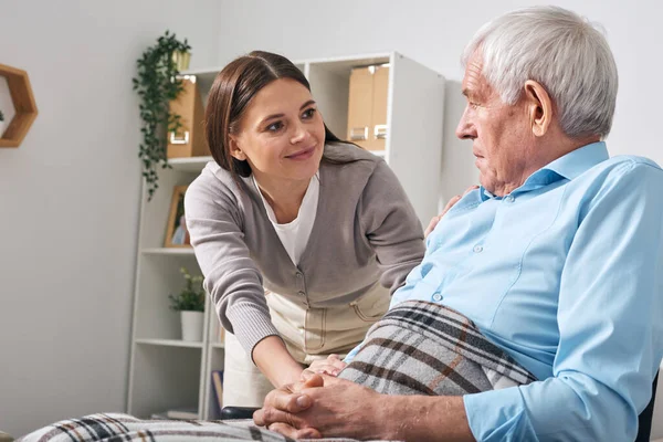 友善的年轻女性护理专家在照顾老年人时询问老年人的需求 — 图库照片