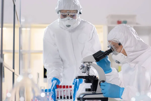 Científico Joven Ropa Trabajo Protectora Mirando Microscopio Mientras Estudia Nuevo —  Fotos de Stock