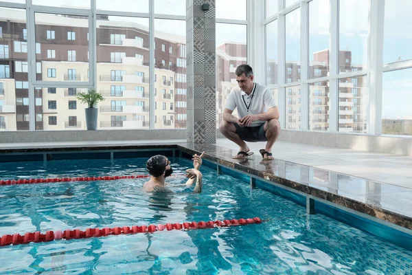 Mature Instructeur Accroupi Sur Bord Piscine Parler Nageur Tout Entraînant — Photo