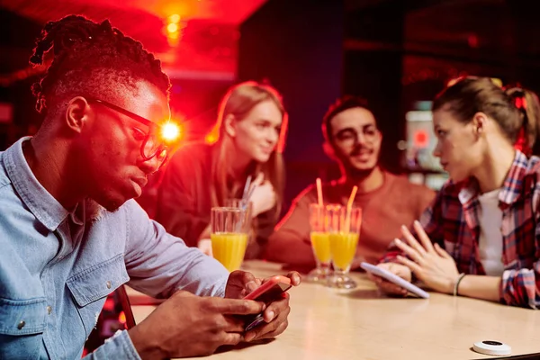 Afrikansk Kille Rulla Smartphone Medan Sitter Vid Skrivbordet Café Bakgrund — Stockfoto
