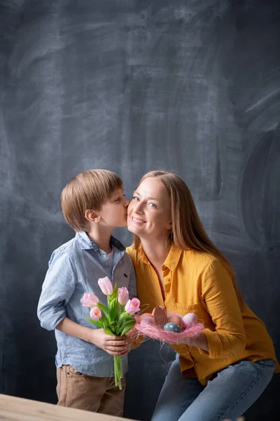 可爱的儿子在复活节庆祝她的时候 亲吻妈妈 给她送郁金香 — 图库照片
