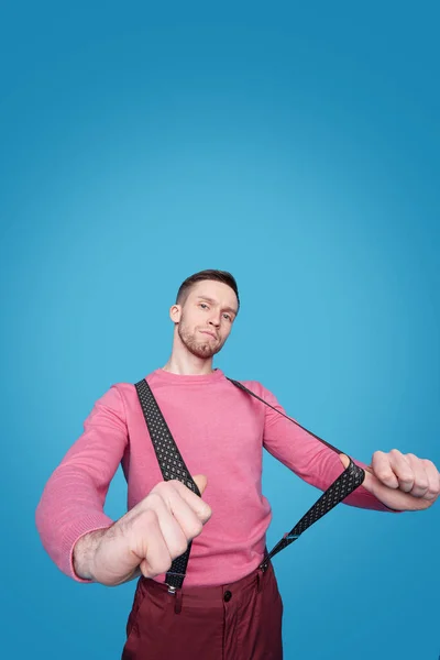 年轻英俊男子站在相机前 身穿粉色休闲装 裤子舒展吊带 — 图库照片