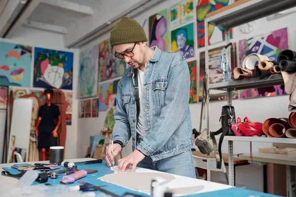 Молодой Ремесленник Шляпе Джинсовой Куртке Джинсах Обрисовывает Бумажный Узор Столом — стоковое фото