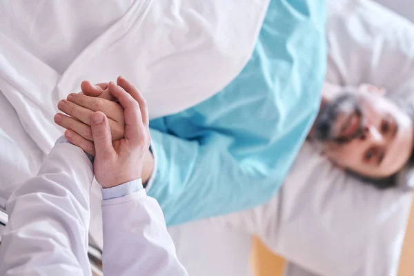 Крупним Планом Лікар Тримає Руки Зрілого Пацієнта Ліжку Підтримуючи Його — стокове фото