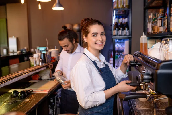 咖啡店或餐馆里快乐迷人的年轻女服务员 用咖啡机和同事一起准备卡布奇诺咖啡 — 图库照片