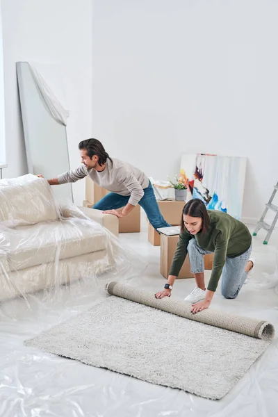 Junge Frau Rollt Teppich Auf Dem Boden Des Wohnzimmers Aus — Stockfoto