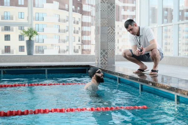 Deneyimli Koç Havuz Kenarında Çömeliyor Yüzücüye Kronometre Ile Zaman Gösteriyor — Stok fotoğraf