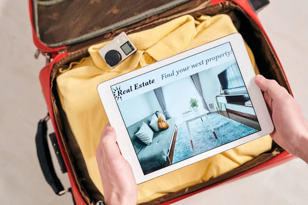 休暇中のアパートのレンタルを選択しながら タブレット上でフラットの認識できない旅行者の写真を表示する上のビュー — ストック写真