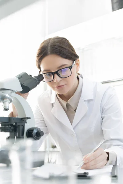 Brunette Vrouwelijke Wetenschappelijk Onderzoeker Whitecoat Het Maken Van Notities Tijdens — Stockfoto