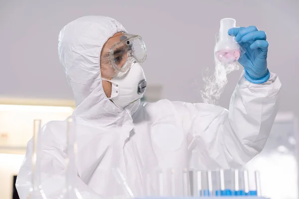 化验室里穿着工作服 眼镜和手套的年轻化学家或药剂师对着吸烟的嘴看 — 图库照片