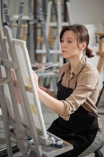 Menina Bonita Avental Olhando Para Pintura Inacabada Enquanto Sentado Frente — Fotografia de Stock
