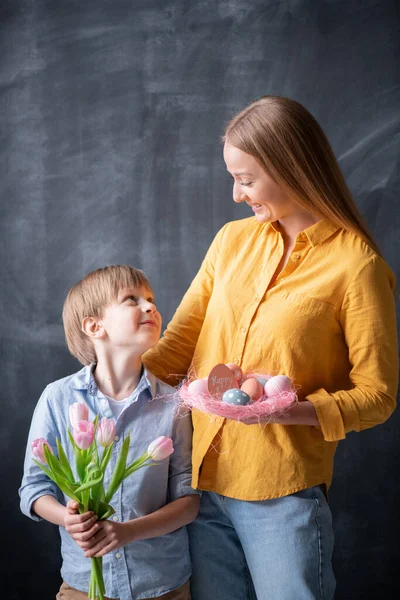 Positieve Jonge Moeder Met Paasnest Haar Zoon Met Boeket Tulpen — Stockfoto