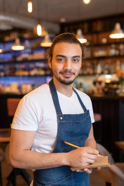 Young Successful Waiter Apron Making Notes Notepad While Taking Order — Stock Photo, Image