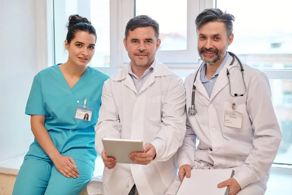 Team Erfahrener Ärzte Uniform Sitzt Auf Fensterbank Krankenhaus Und Blickt — Stockfoto