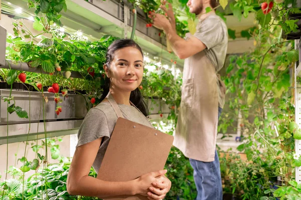 Retrato Joven Trabajadora Confiada Sonriente Pequeño Invernadero Parada Estante Planta —  Fotos de Stock